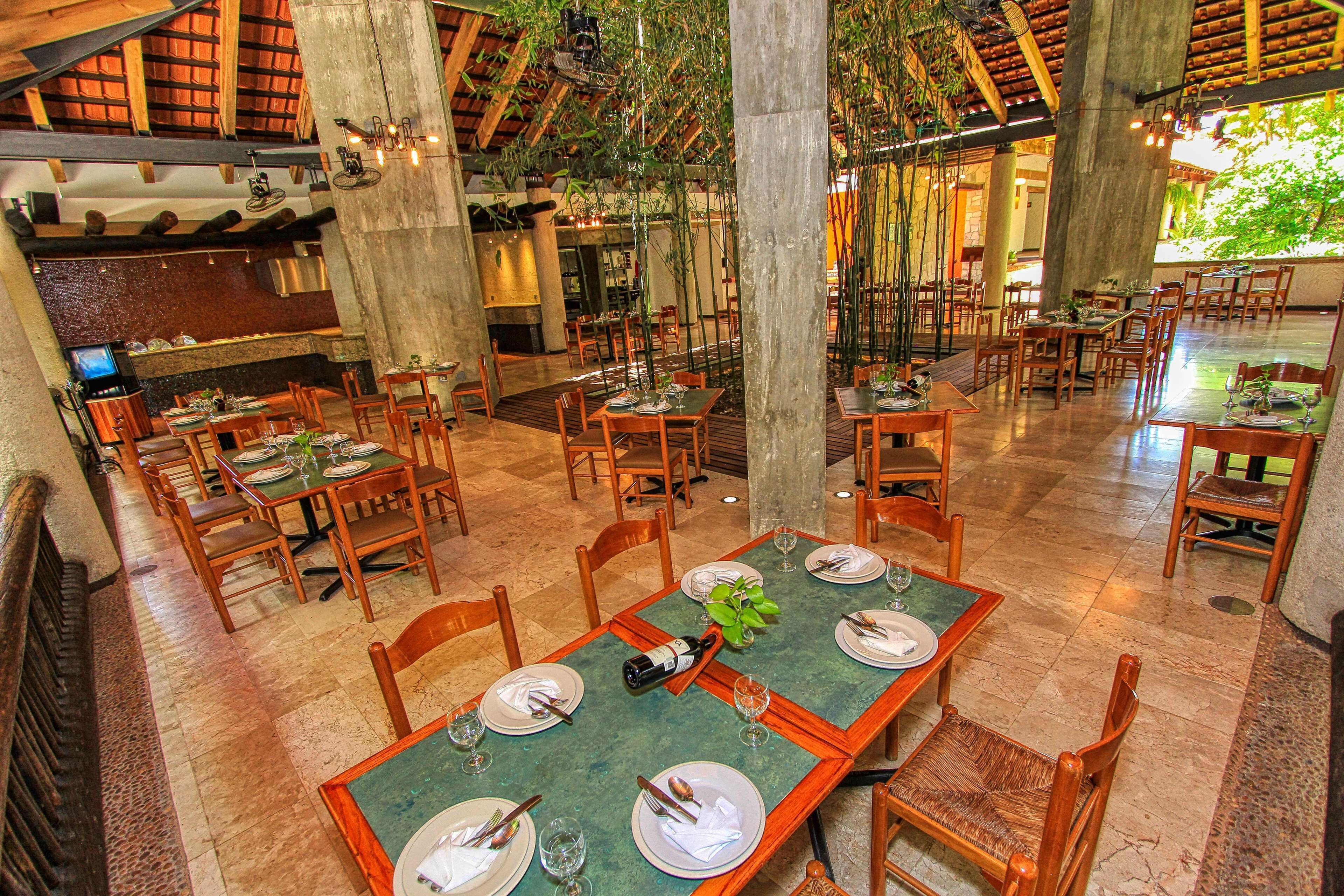 A spacious restaurant with high ceilings, wooden tables, and chairs.