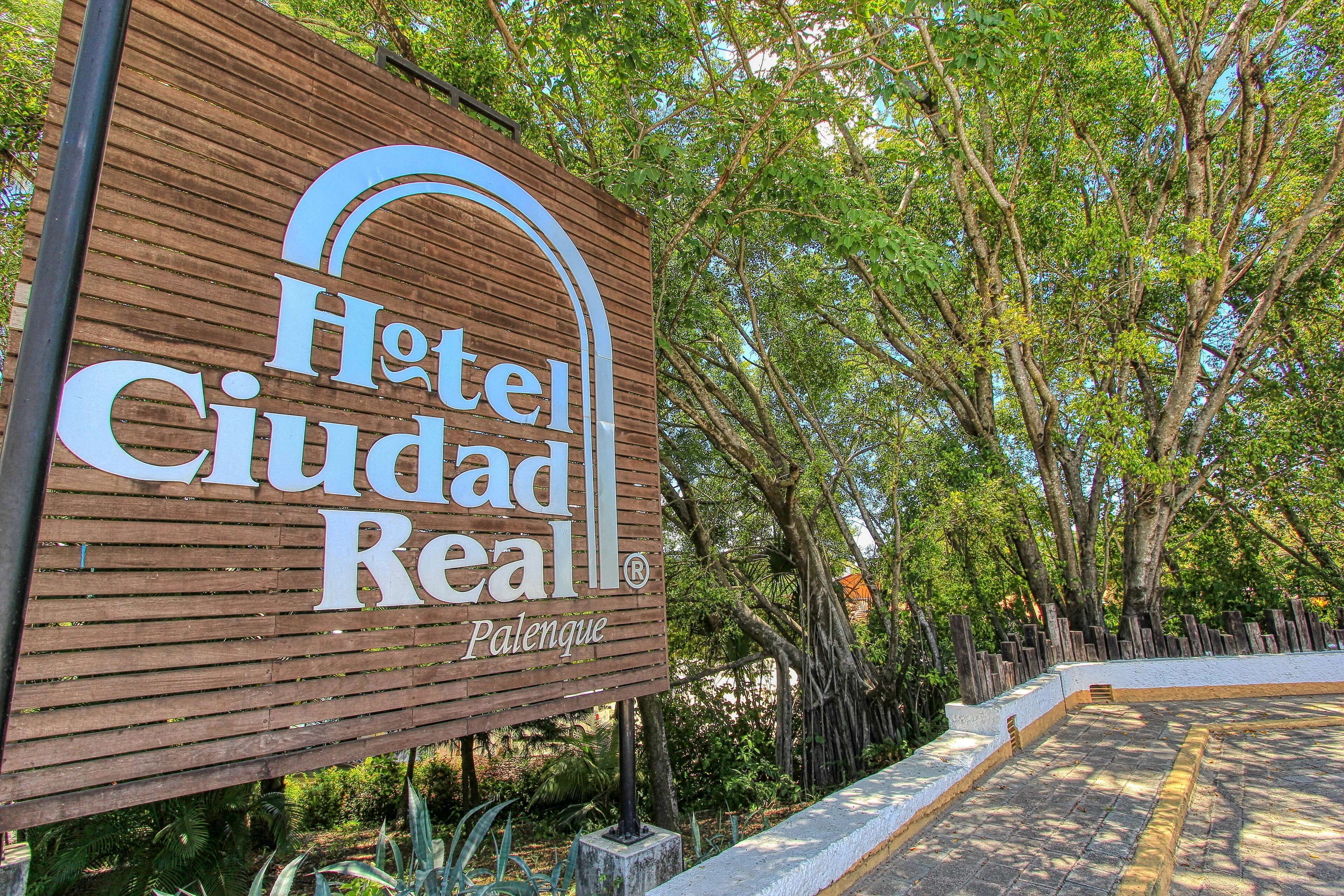 A wooden sign for Hotel Ciudad Real with a curved arch design.