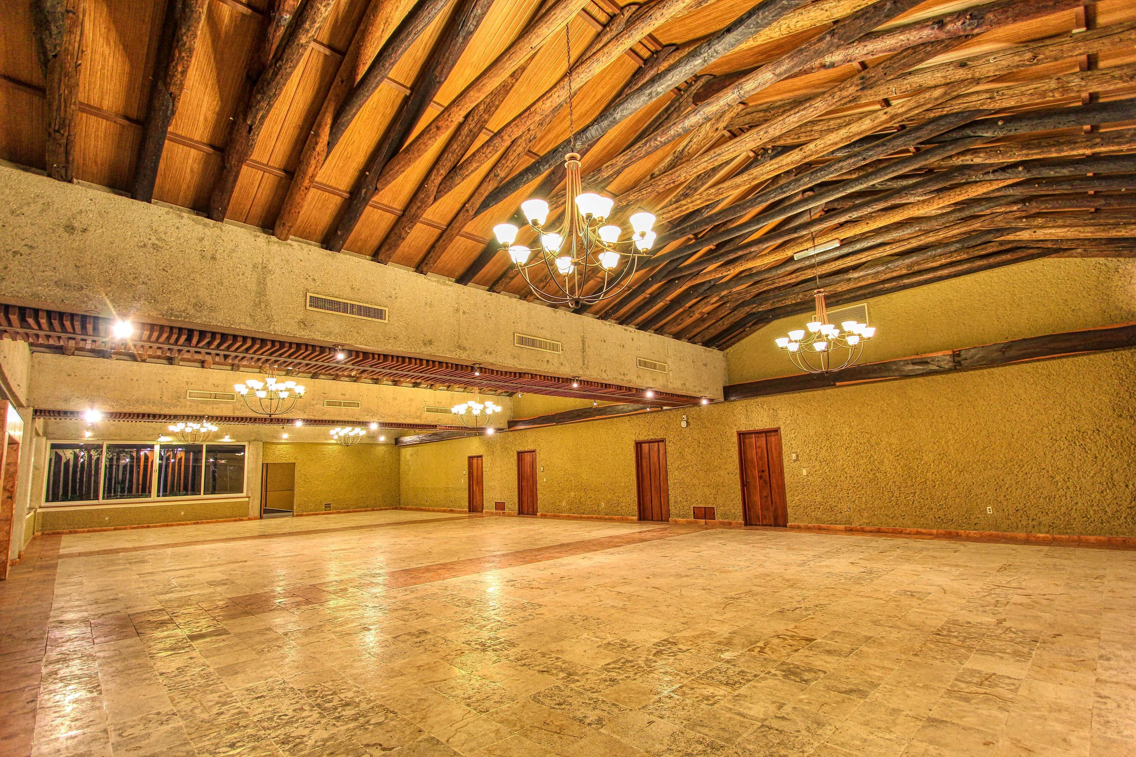 A spacious hall with a high wooden ceiling and chandeliers.