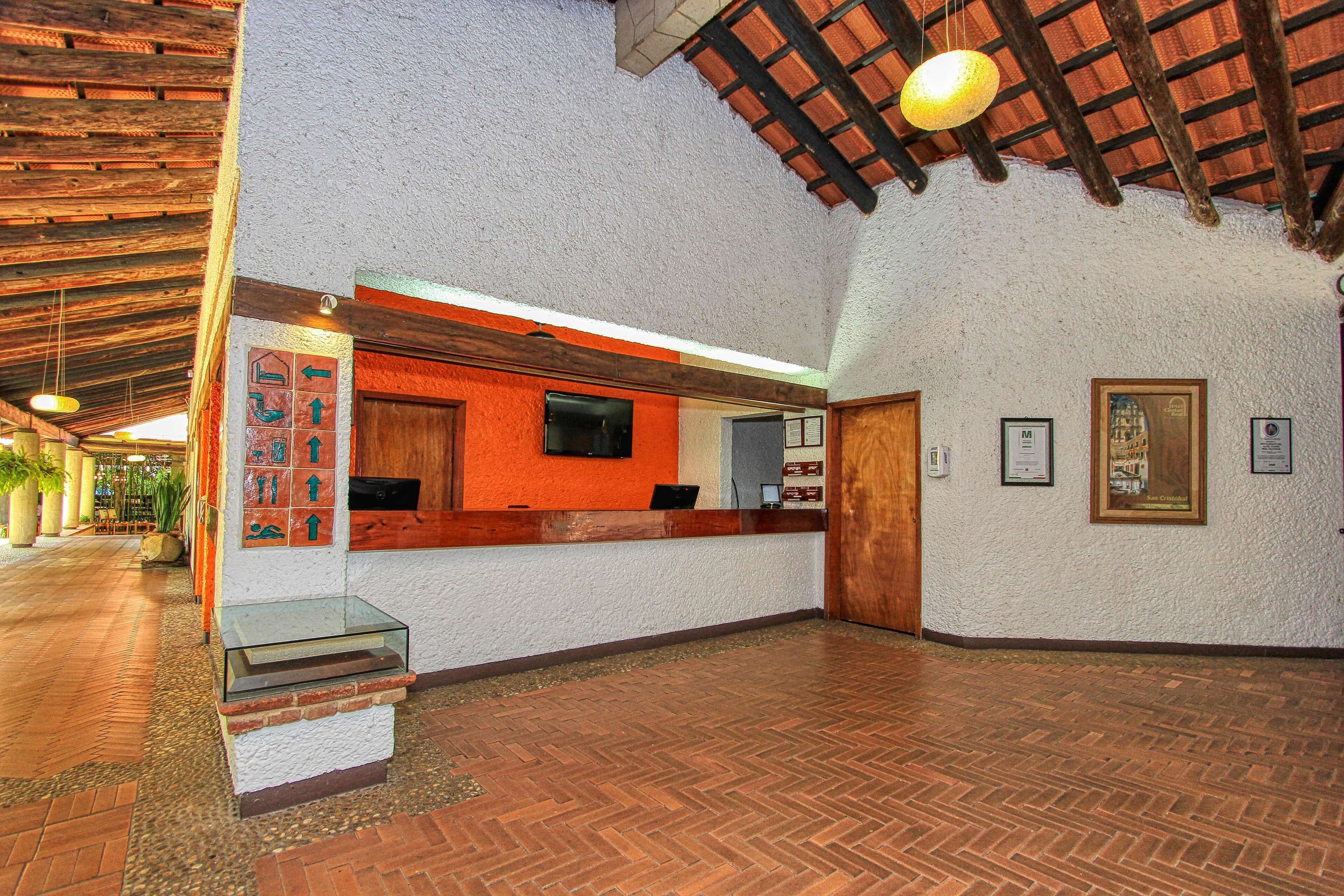 Un hall d’entrée avec un comptoir de réception, un escalier et un sol carrelé.