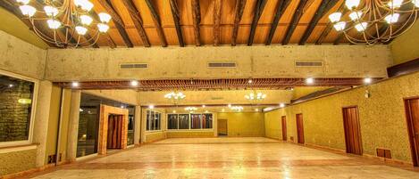 A spacious hall with a high ceiling, wooden beams, and chandeliers.