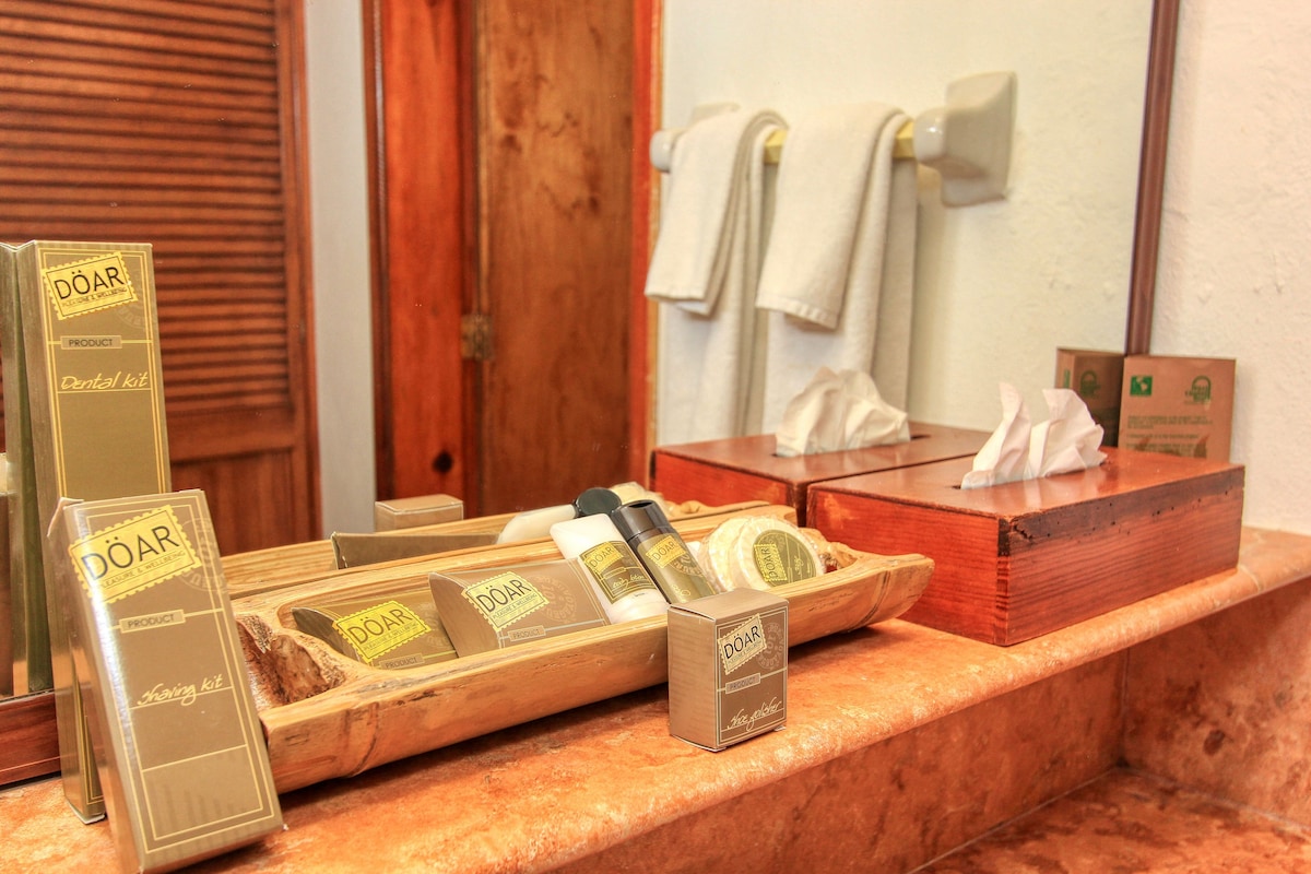 A bathroom vanity with a wooden tray holding various DOAR products, a mirror, and a towel rack.