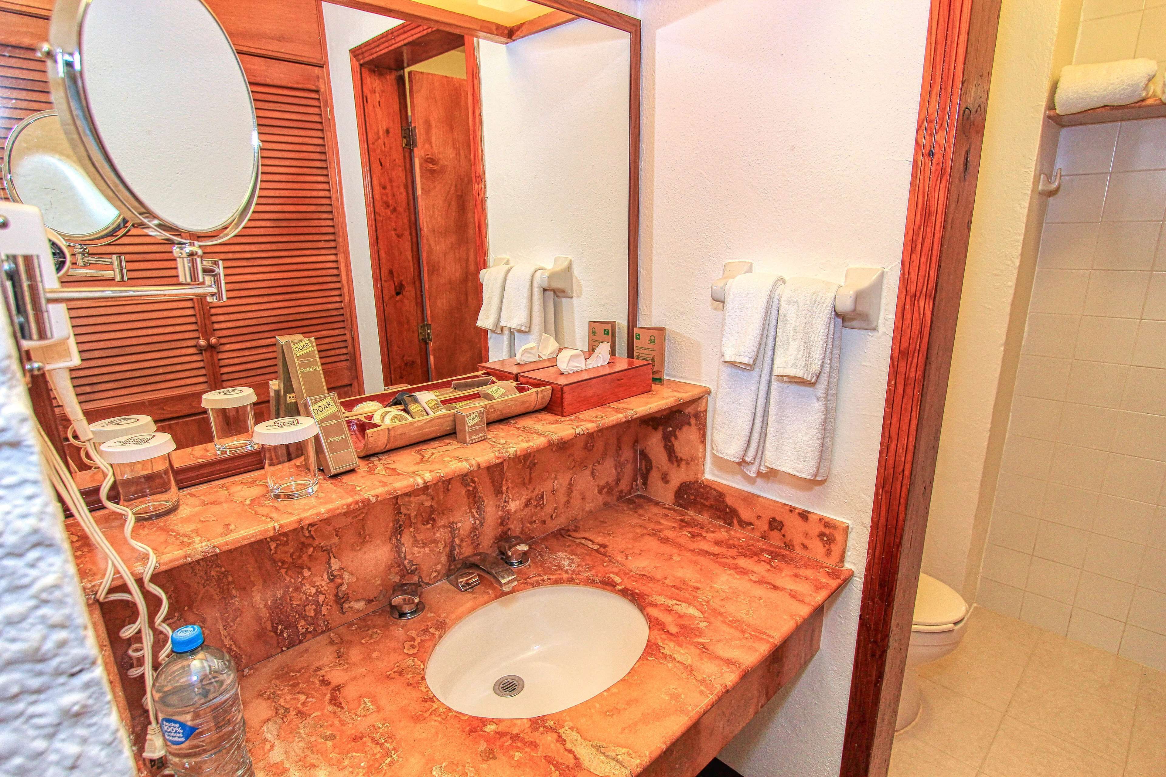 Un bagno con un lavabo in marmo, due specchi, una porta in legno e un porta asciugamani.