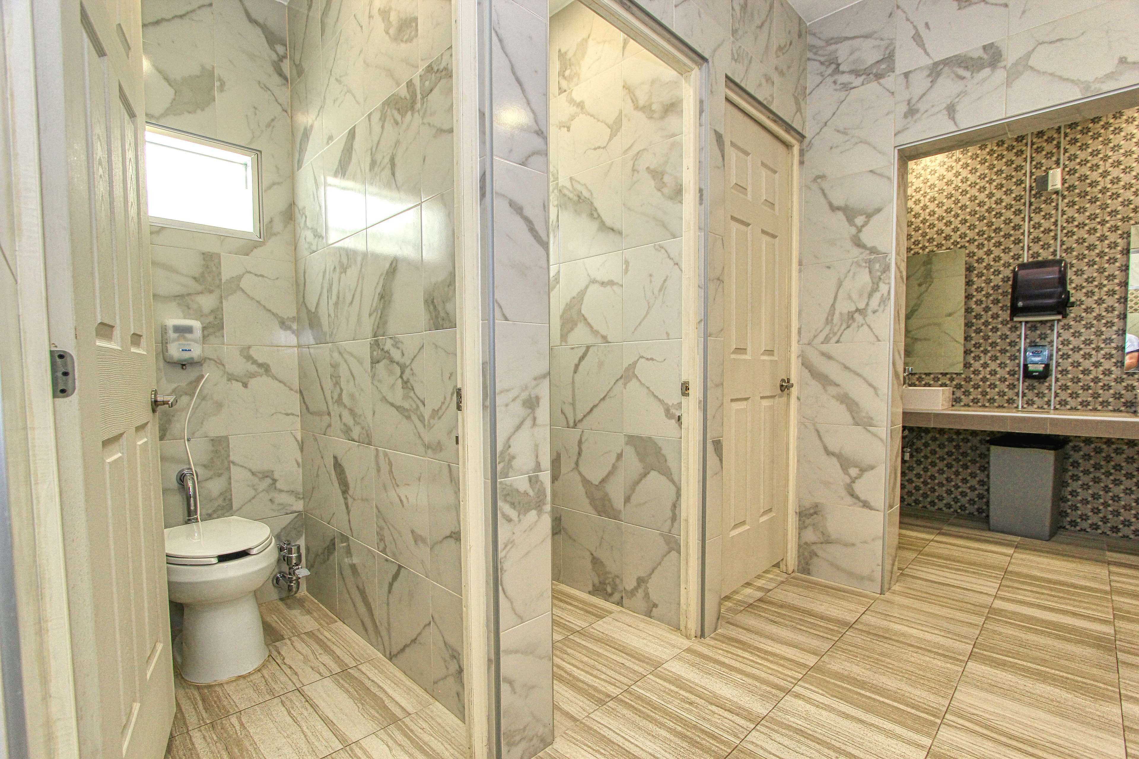 Un baño con paredes de mármol, un inodoro, un lavabo y un espejo.