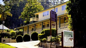 A two-story motel with a balcony on the upper floor, surrounded by lush greenery and well-maintained bushes. - Riverview Boutique Motel (Nambucca Heads)