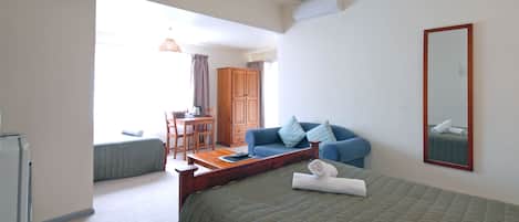 Una habitación de hotel con cama, escritorio, silla y armario.
