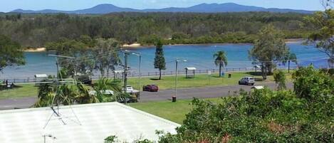 Vista de una zona costera con un estacionamiento, una playa y una cadena montañosa al fondo.