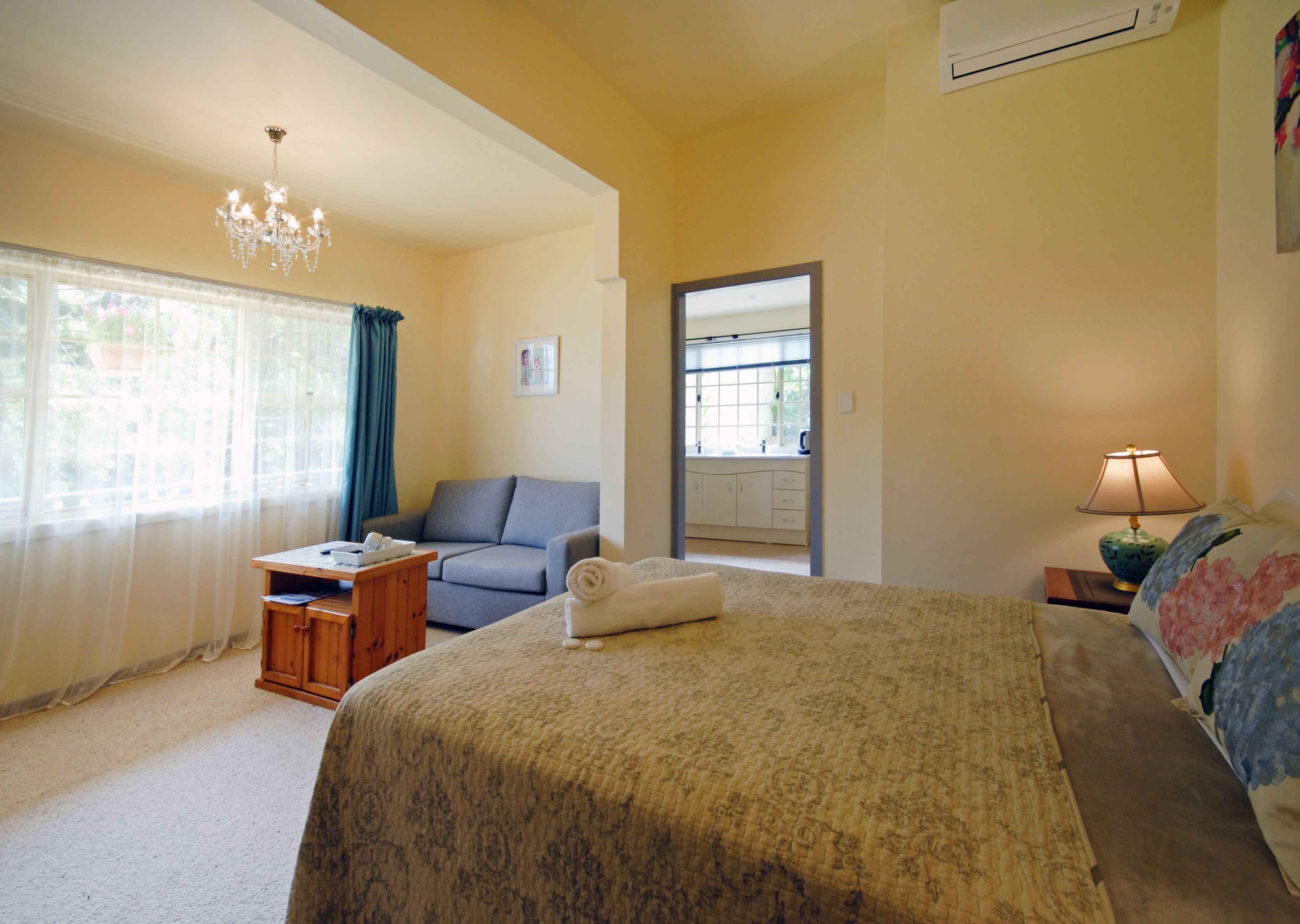 Quarto com uma cama, escrivaninha, cadeira, abajur e janela com cortinas.