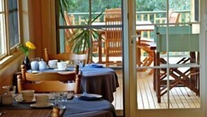 A dining area with tables set for two, a large window, and a view of the outdoors. - Riverview Boutique Motel (Nambucca Heads)