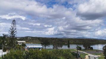 Une vue d’un lac, avec un bâtiment portant l’inscription « LILAC STREET HOUSE » au premier plan, entouré d’arbres et d’une zone de stationnement.