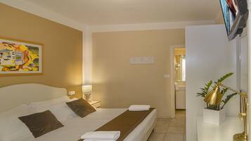 Una habitación de hotel con una cama, una mesita de noche, una lámpara y un cuadro en la pared.