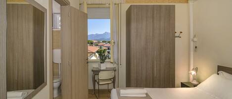 Habitación de hotel con una cama, un escritorio, una silla y vistas a la montaña.