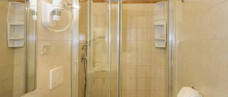 Un baño moderno con ducha de vidrio, un lavamanos blanco y un inodoro.