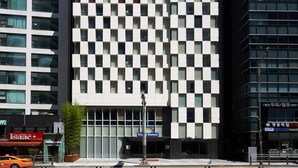 Un hotel con una fachada distintiva a cuadros, un llamativo letrero de Days Hotel y un moderno edificio de vidrio a la derecha.