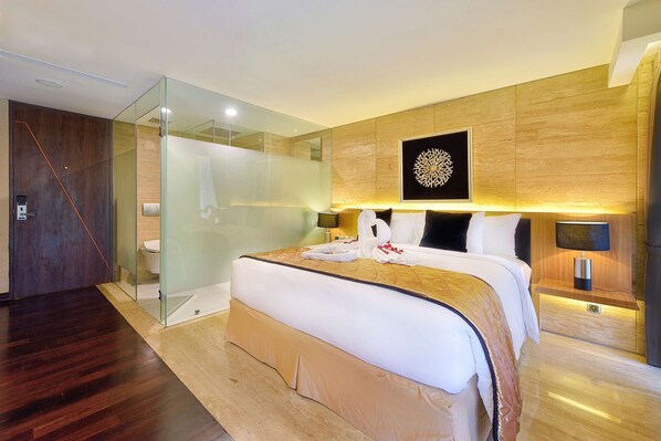 Una habitación de hotel moderna con una cama grande, cabina de ducha de vidrio y una pared decorativa de madera.