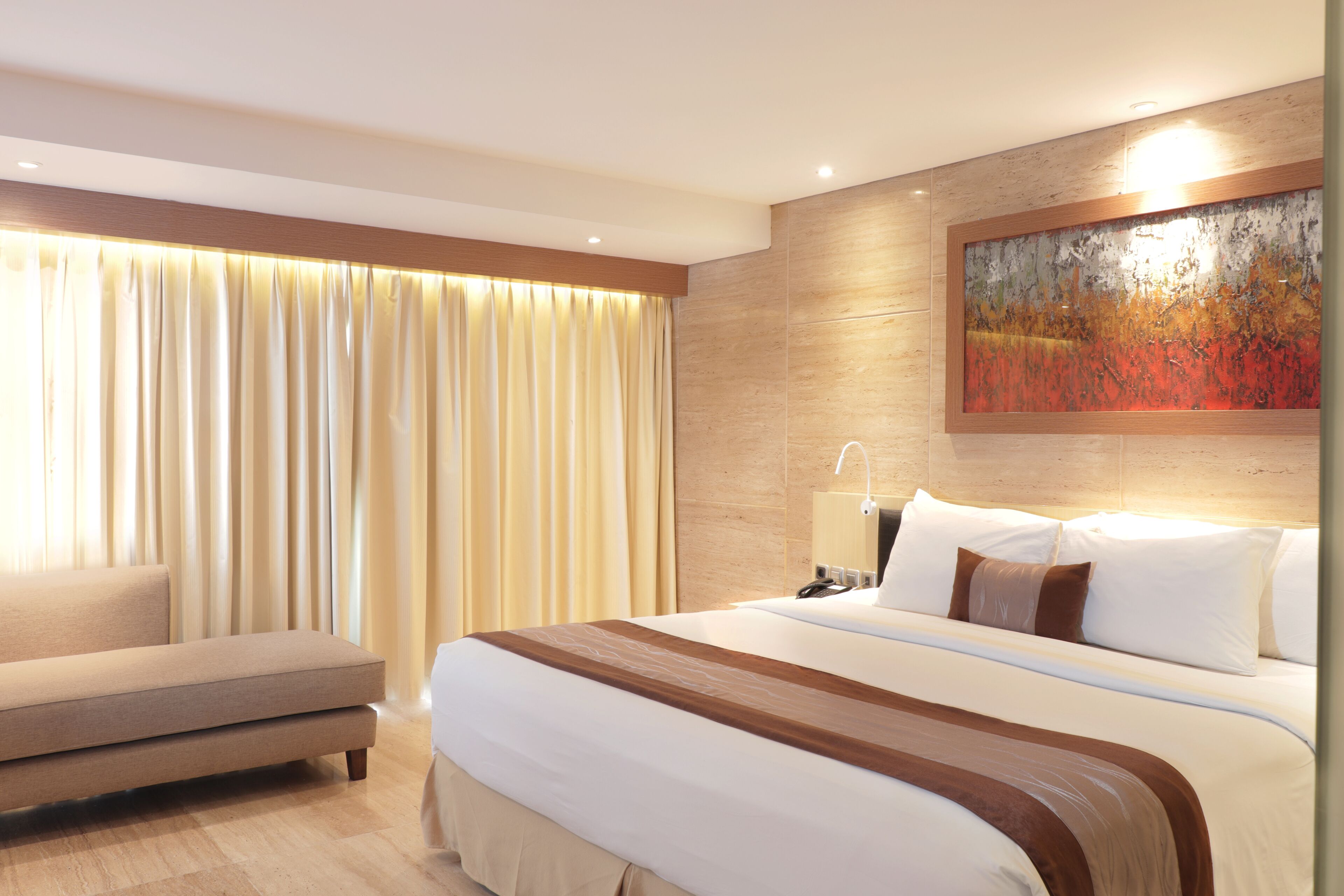Une chambre d’hôtel avec un grand lit, un canapé, un tableau au mur et une fenêtre recouverte de rideaux.