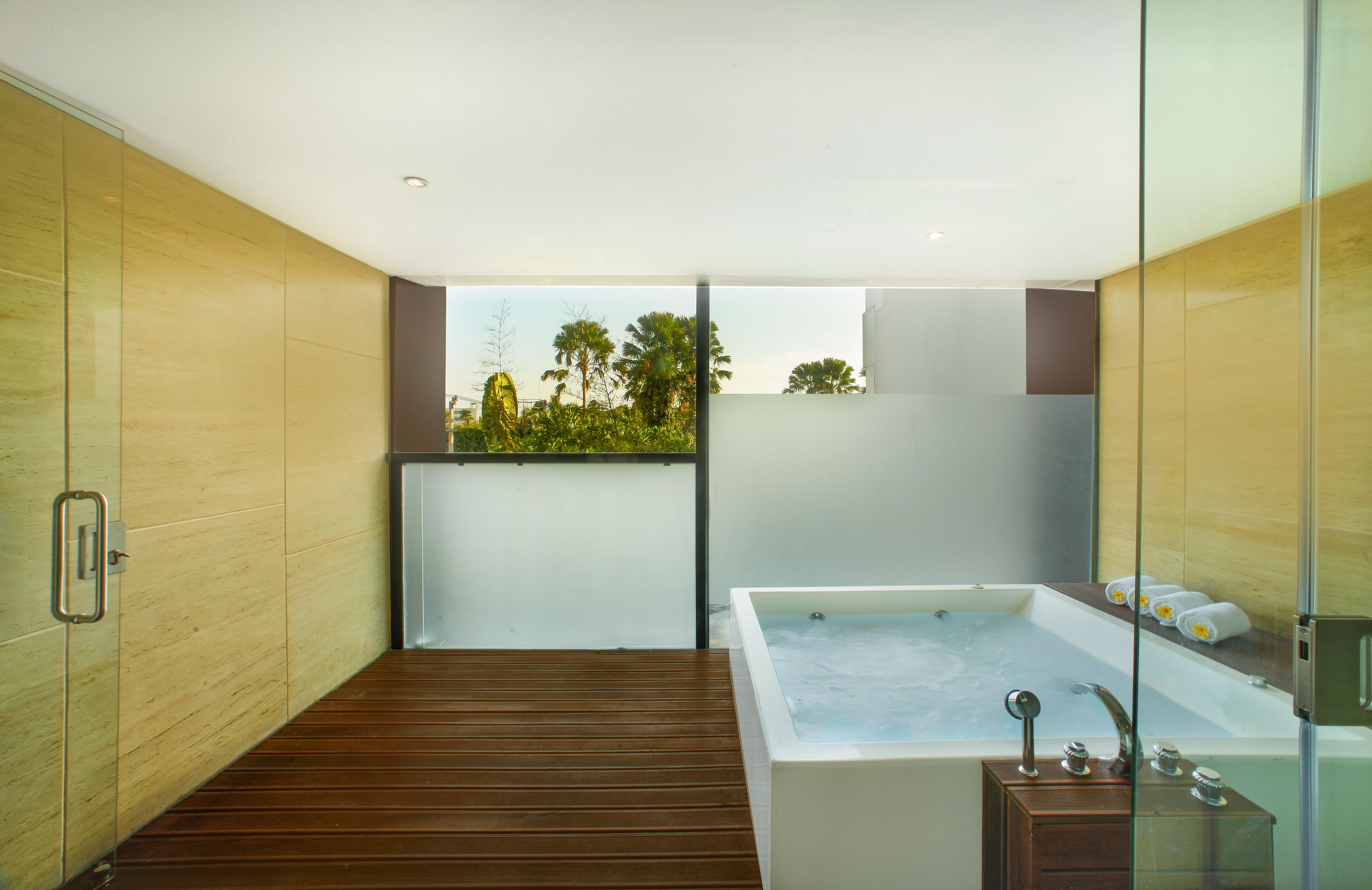 Un baño moderno con piso de madera, una bañera grande y un box de ducha de vidrio.