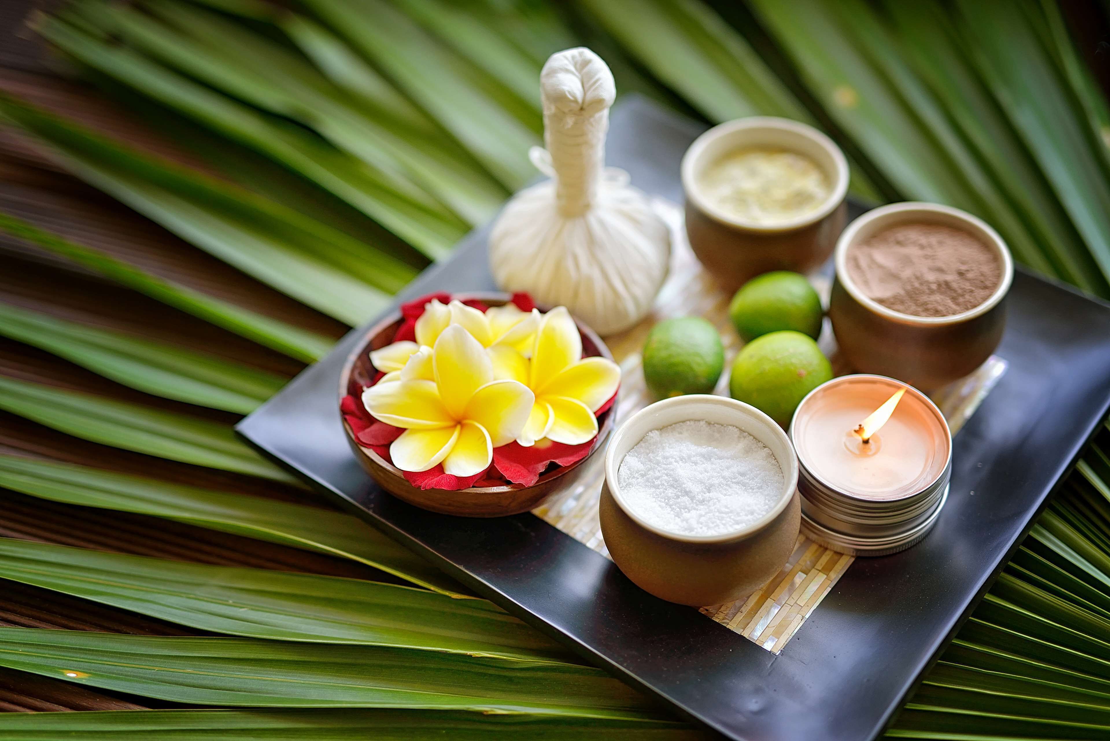 Un vassoio con un fiore, una candela e diversi prodotti da spa.
