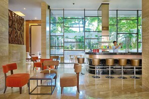 Relax in our stylish lobby, featuring a bar, seating area, and floor-to-ceiling windows overlooking lush greenery.