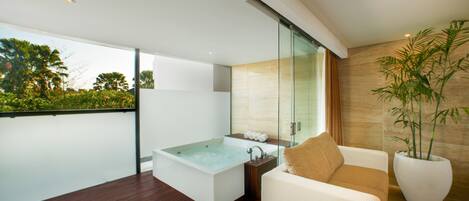 Une salle de bain moderne avec une grande baignoire, une douche en verre et une plante en pot.