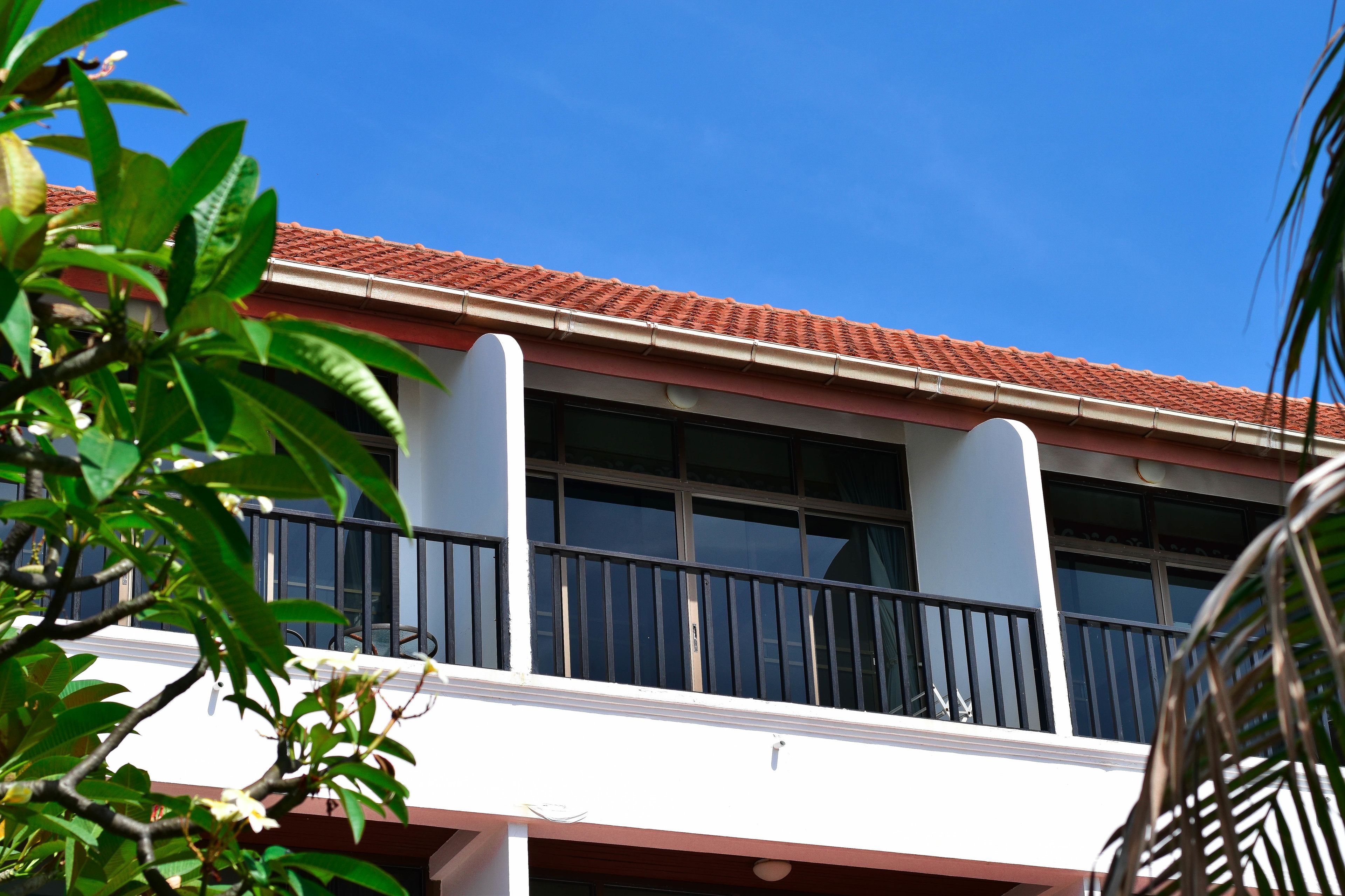A building with a red-tiled roof, white walls, and a balcony with black railings.