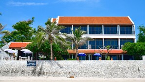 A two-story building with a red-tiled roof, large windows, and a stone wall in the foreground. - Sea Memories White Sand Beach Hotel (Hua Hin)