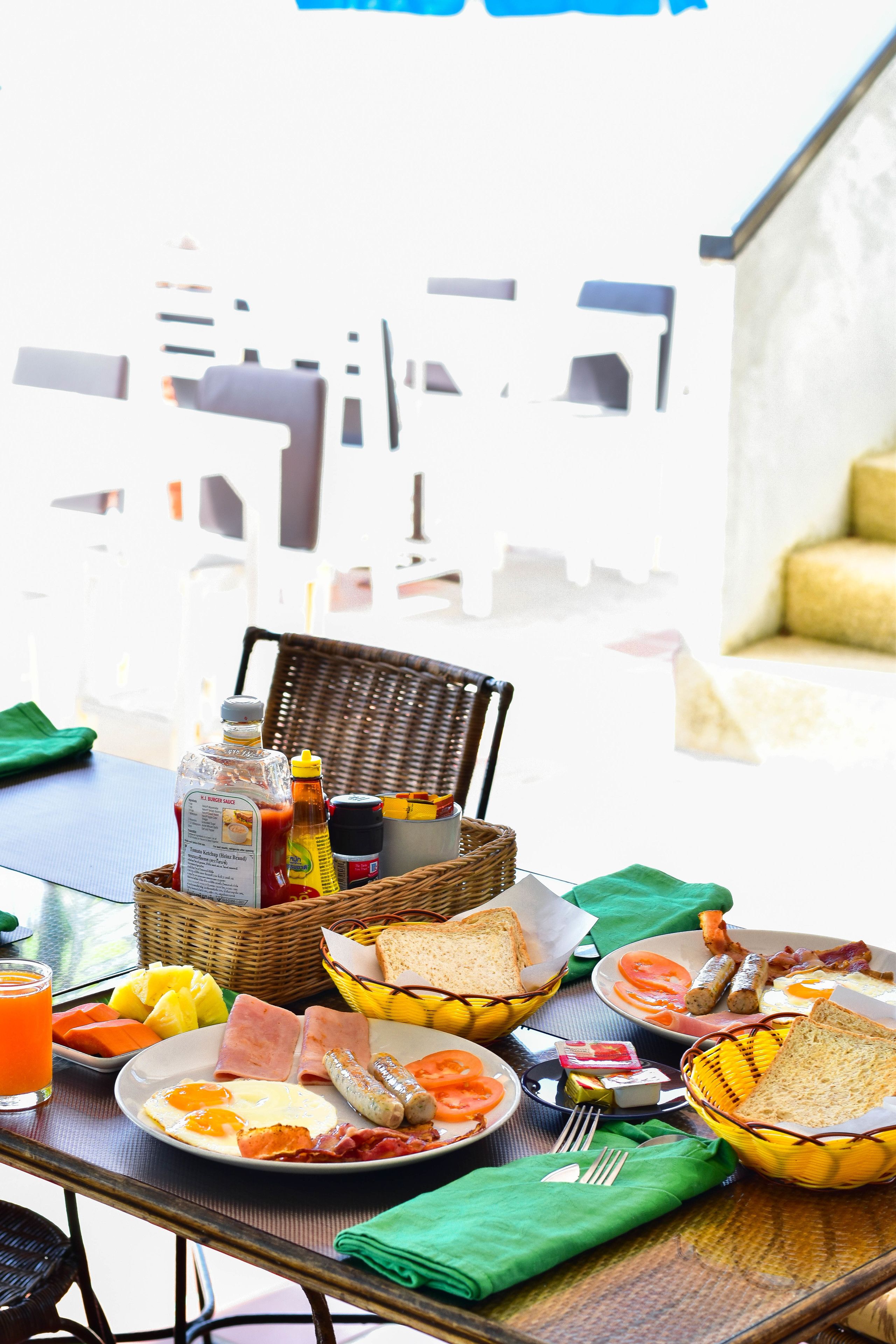 Una mesa de desayuno con diversos alimentos y una silla de mimbre.