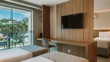 A hotel room with two beds, a TV mounted on a wooden panel, a desk, and a chair.