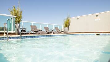 Una piscina al aire libre, sillones reclinables de piscina