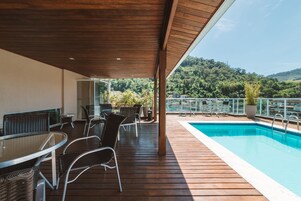 Un'area esterna coperta con piscina, un pontile in legno e mobili da giardino.