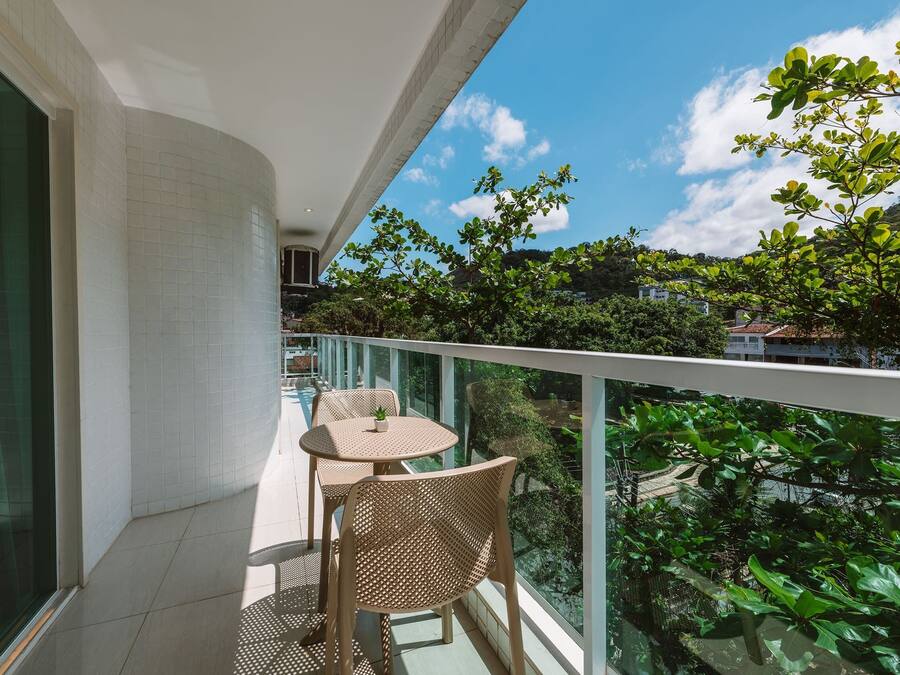 A balcony with a glass railing, a small table, and two wicker chairs.
