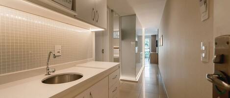 Una cocina moderna con un lavamanos de acero inoxidable, armarios blancos y un microondas sobre la encimera.