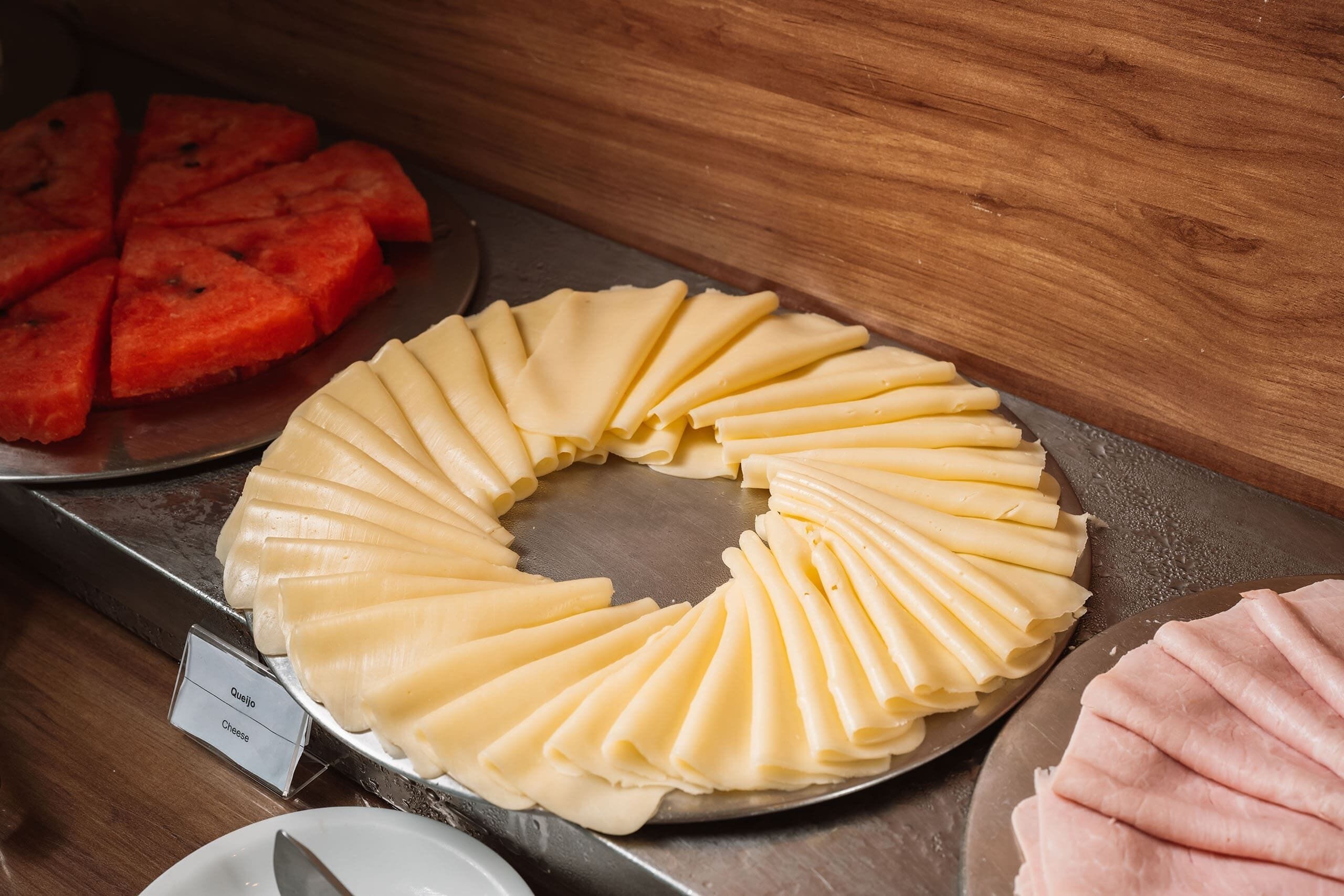 A display of sliced cheese and watermelon arranged on a metal tray.