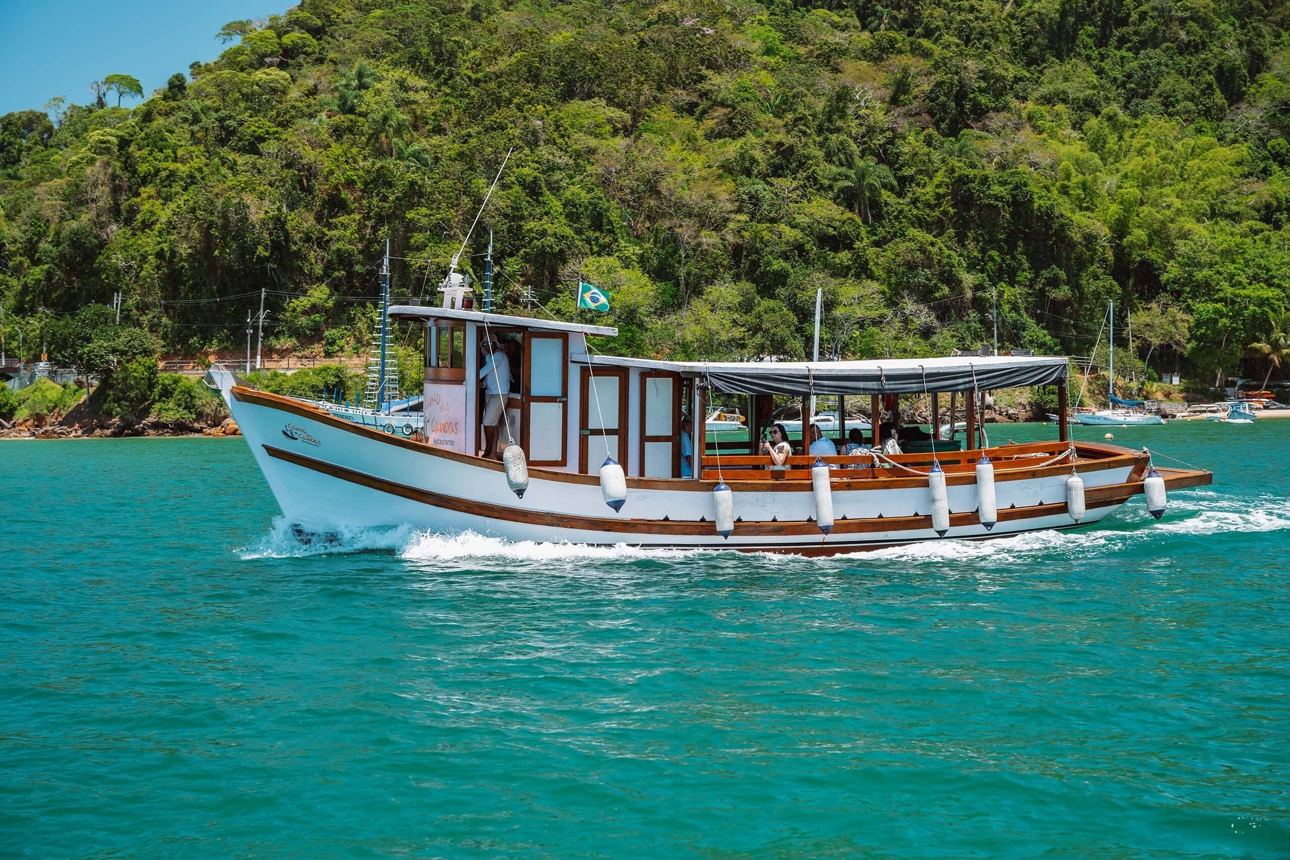 Um barco com cabine e deck aberto, navegando em águas turquesa cristalinas.
