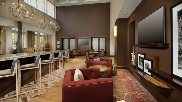 A spacious lobby with a bar area, seating arrangements, and a large flat-screen TV mounted on the wall.