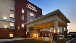 A hotel entrance with a covered driveway, clear signage, and a parking area.