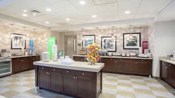 A modern kitchen with a central island, equipped with a coffee machine, tea station, and a fruit bowl.