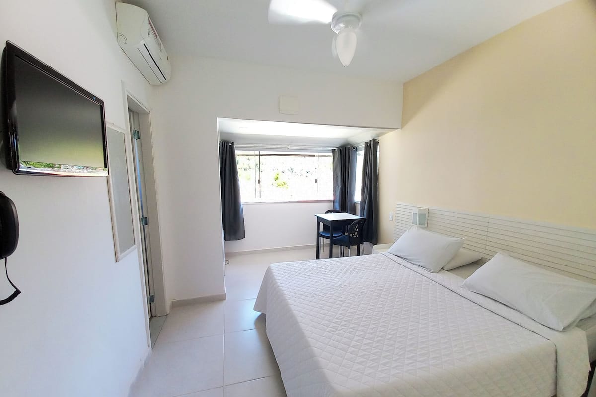 Una habitación de hotel con cama, escritorio y televisión.