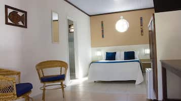 Une chambre à coucher avec un lit, deux fauteuils en osier, un ventilateur de plafond et une horloge murale.