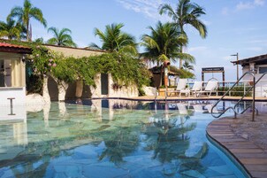 A clear swimming pool with lounge chairs and palm trees.