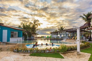 A swimming pool area with a sunset view, lounge chairs, and a bar area. - Pousada Daleste (Angra dos Reis)