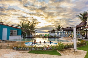 A swimming pool area with a sunset view, lounge chairs, and a bar area.