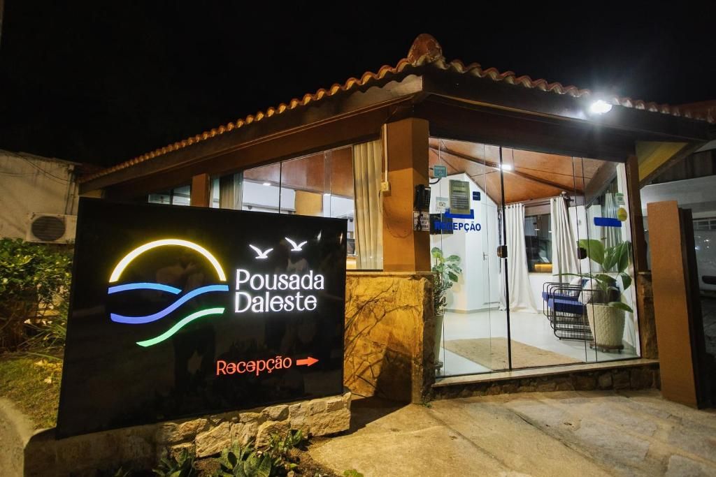 A reception area with a sign for Pousada Daleste, featuring a logo with a sun and waves, and an arrow pointing to the reception.