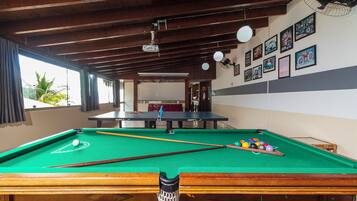 A pool table with balls and cues, a ceiling fan, and framed pictures on the wall.