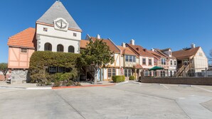 A building with a clock tower, a parking lot, and a row of houses with red roofs. - Royal Copenhagen Inn (Solvang)