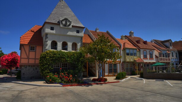 A building with a clock tower, multiple windows, and a red-tiled roof. - Royal Copenhagen Inn (Solvang)