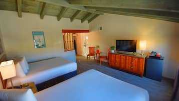 Une chambre d’hôtel avec deux lits, une commode en bois, un téléviseur et une petite table avec des chaises.