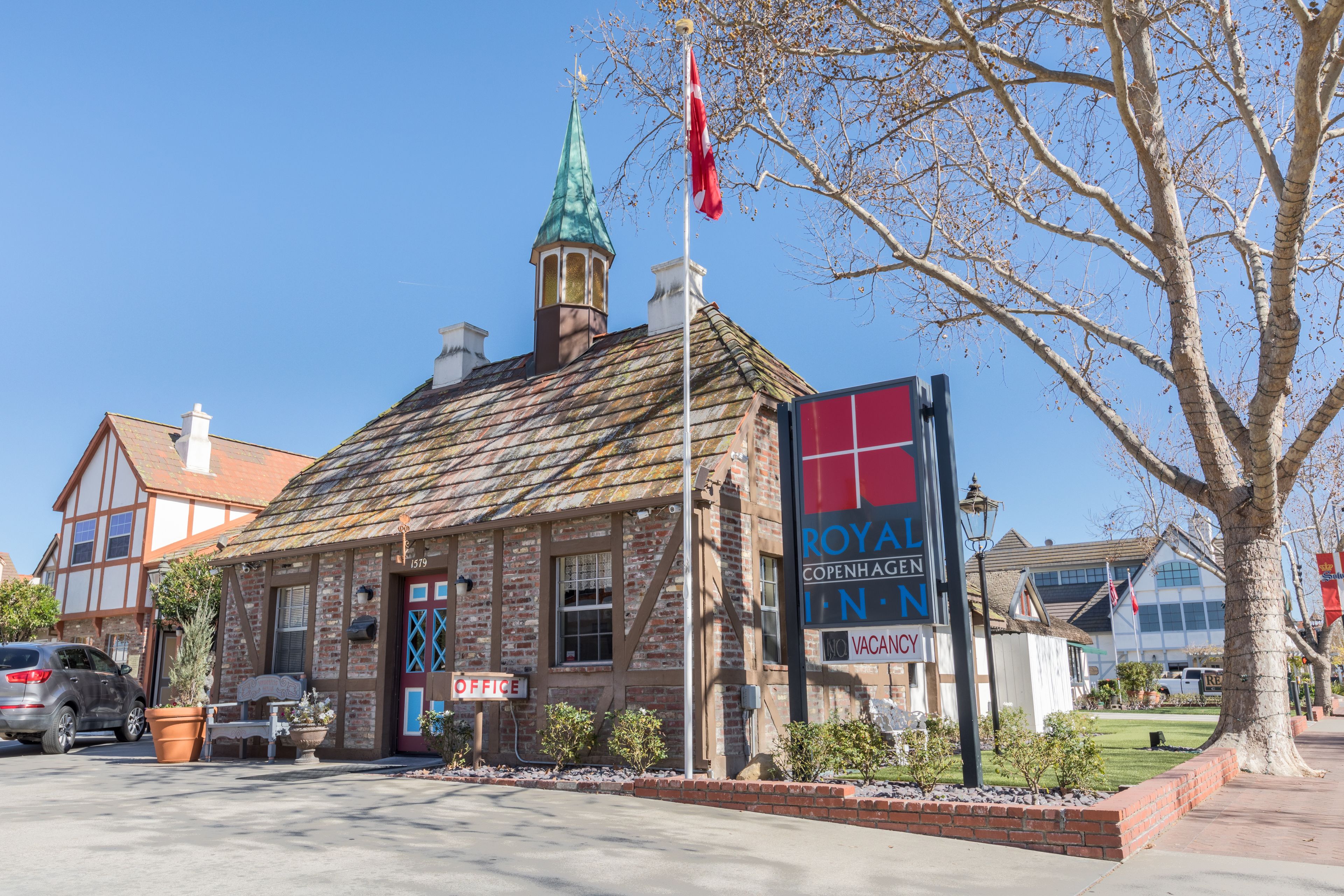 A historic building with a traditional facade, a prominent clock tower, and a sign indicating it is a hotel.