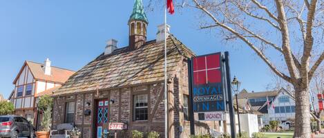 A historic building with a traditional facade, a prominent clock tower, and a sign indicating it is a hotel.