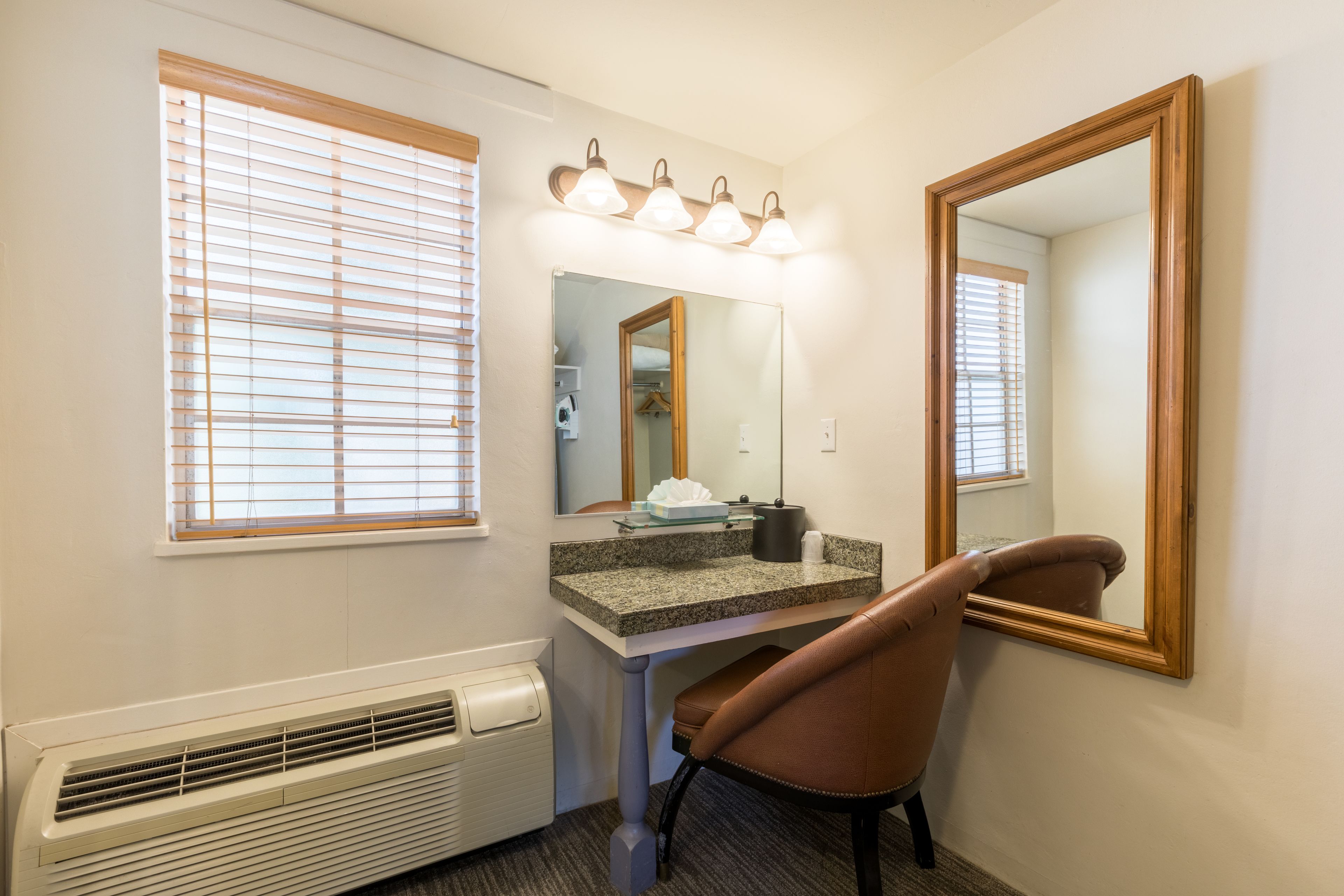 A bathroom with a vanity, mirror, and window with blinds.